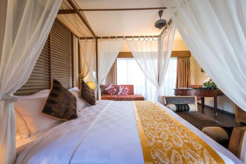 - une chambre avec un grand lit et des rideaux dans l'établissement Tok Aman Bali Beach Resort @ Beachfront, à Kampong Ayer Tawar