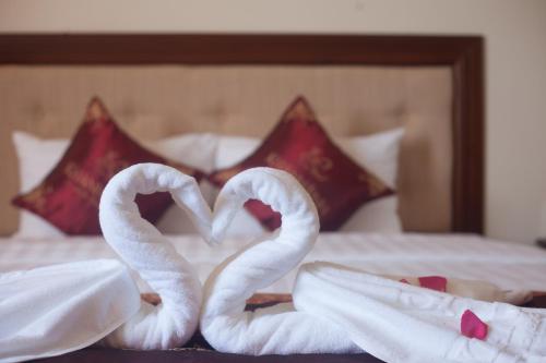 two towel swans making a heart on a bed at Khanh Linh Hotel in Pleiku