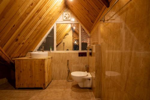 a bathroom with a toilet and a sink and a window at Ishan Log Huts-A boutique home stay in Banjār