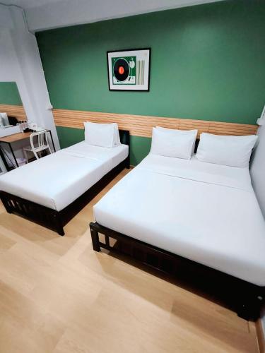 two beds in a room with a green wall at 9TY hotel (ninety hotel) in Bangkok