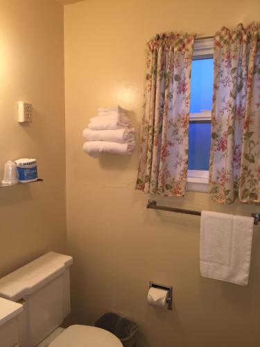 a bathroom with a toilet and a window with towels at Sharon Motel in Wells
