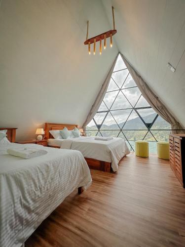 two beds in a room with a large window at Eco Vibe Resort in Rattota