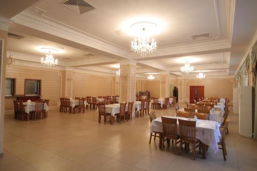 jadalnia ze stołami, krzesłami i żyrandolami w obiekcie Hotel Alma-Ata w mieście Borowoje