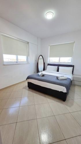 a bedroom with a large bed in a white room at Sunset Poolside Apartment with Pool facility in Larnaca