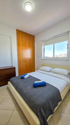 a bedroom with a large bed with blue pillows on it at Sunset Poolside Apartment with Pool facility in Larnaca