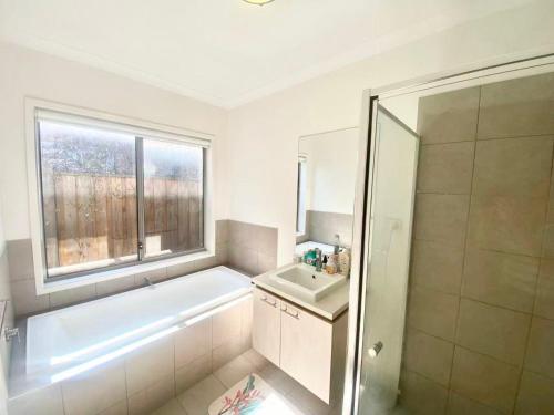 a bathroom with a tub and a sink and a window at Point Cook Homestay House in Point Cook
