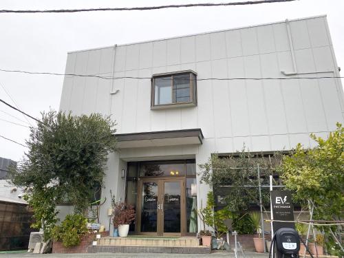 a white building with a door in front of it at Pension Yumigahama in Minamiizu