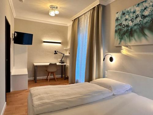 a bedroom with a bed with a desk and a window at Hotel Villa Solln - free parking in Munich