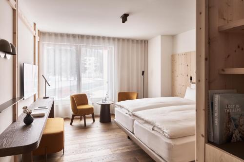 a bedroom with a bed and a desk and a window at Laudinella Apartments in St. Moritz