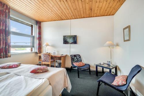 a hotel room with two beds and a desk and chairs at Hotel Pinenhus in Glyngøre