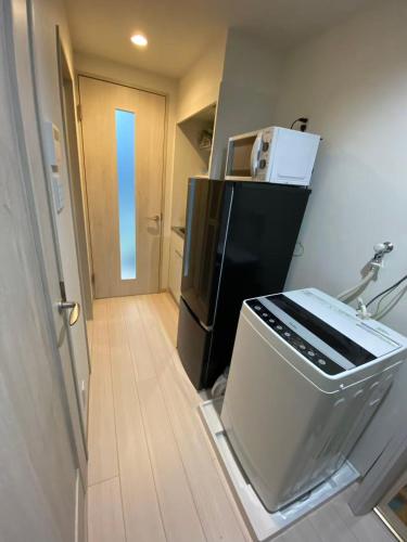 a kitchen with a refrigerator and a microwave at 大阪難波ELLY-ten in Osaka
