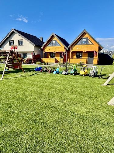 a yard with a house and a playground at Delfinek - Domki Apartamenty in Gąski