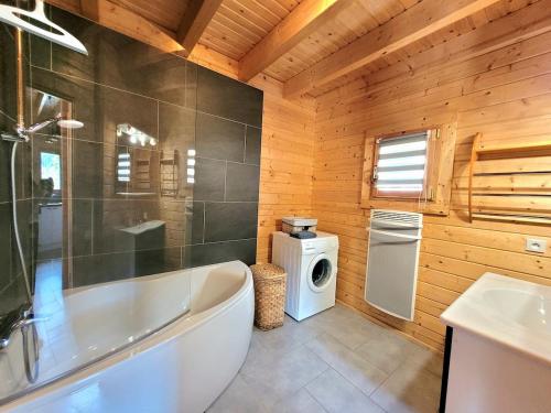 a bathroom with a tub and a washing machine at Chalet Cocoon 6p avec Spa privé in Rochesson