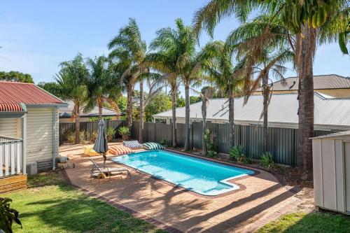 a backyard with a swimming pool and palm trees at Bedford Pool Oasis - Comfort near CBD & Airport in Perth