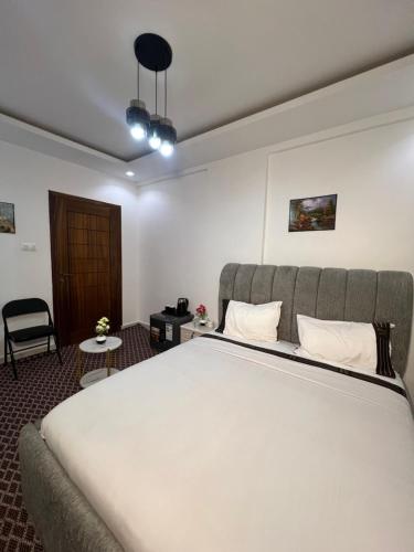 a bedroom with a large white bed and a chair at FASA RESIDENCE Dakar CHAMBRE TERANGA in Dakar