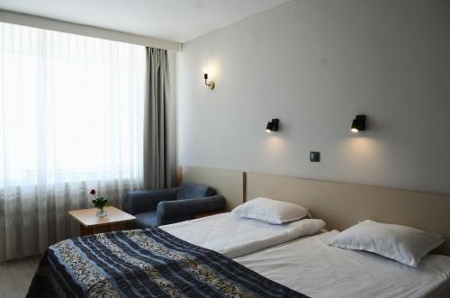 a hotel room with two beds and a chair at Hotel Oasis - Beach Access in Balchik