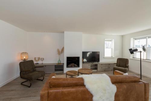 a living room with a couch and chairs and a tv at Welcome in - Familiehuis met ruim terras en speelweide I Oostkapelseweg 32, Serooskerke 'Ooievaar' in Serooskerke