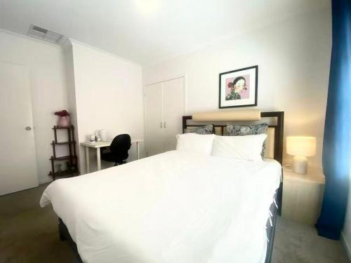 a bedroom with a large white bed and a desk at Point Cook Homestay House in Point Cook