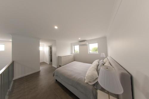 a white bedroom with a bed and two windows at Private Mezzanine Bedroom, Soaring Ceilings, Sleeps 3, Walk to Cafes, 15 min to Bunbury in Australind