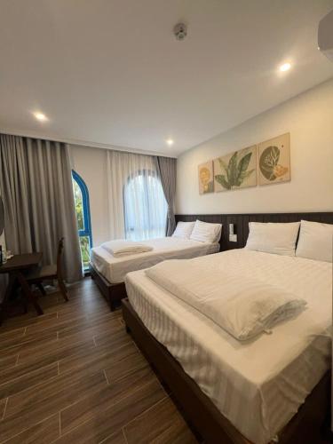 a hotel room with two beds and a desk at Nhã Hotel A in Thôn Mỹ Phước