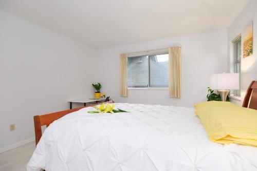 a white bedroom with a large white bed with flowers on it at Private Room with Full Amenities in Cozy House in Vancouver
