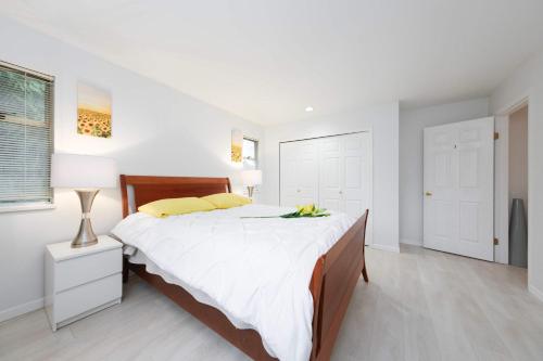 a white bedroom with a large bed with yellow pillows at Private Room with Full Amenities in Cozy House in Vancouver
