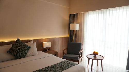 a hotel room with a bed and a chair and a window at Tusita Boutique Hotel in Kuta