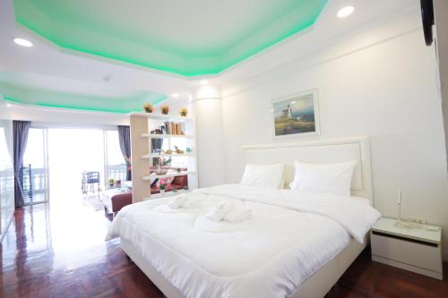a bedroom with a white bed with a green ceiling at Sky beach view in North Pattaya