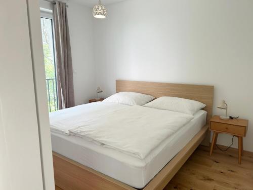 a bedroom with a large white bed with a wooden headboard at Feigenterrasse beim Semmering - Tiny House in Schlagl