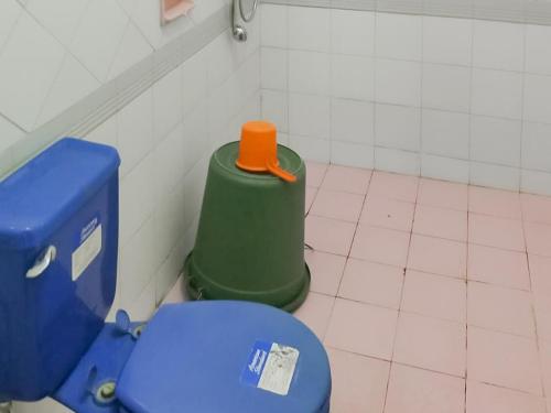 a bathroom with a blue toilet and a green trash can at Villa Anyelir Yustik Mitra RedDoorz in Selabintana