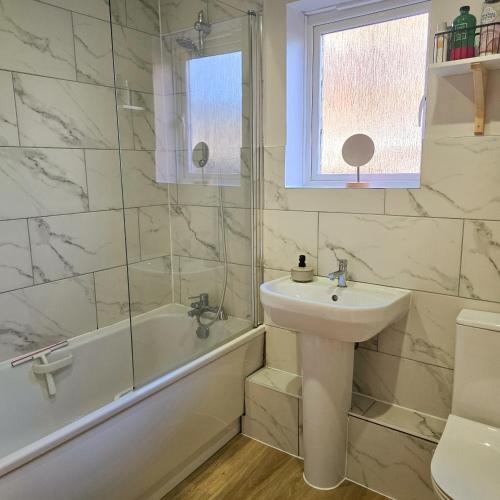 a bathroom with a sink and a tub and a toilet at Welcome Home in Royston