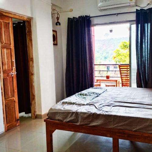 a bedroom with a bed and a large window at Dapolihideaway in Dapoli