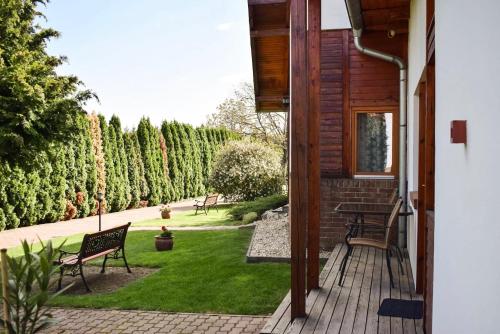 a porch of a house with benches and a garden at SOL Panzió in Bük