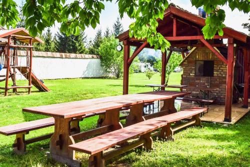 a wooden picnic table in a field with a building at SOL Panzió in Bük