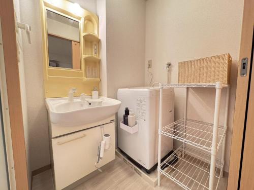 a small bathroom with a sink and a refrigerator at ura アオトハル2 in Okayama