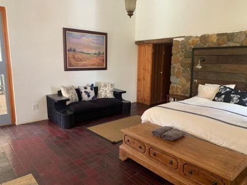 a bedroom with a bed and a bench and a couch at Waterval Karoo Guest Farm in Laingsburg