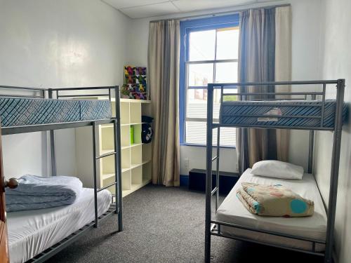 two bunk beds in a room with a window at Jack's Backpackers in Blenheim