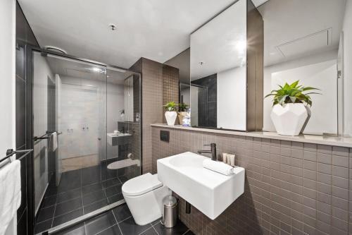 a bathroom with a sink and a toilet and a mirror at Stylish Central Braddon 1 Bed, Pool, Gym, Parking in Canberra