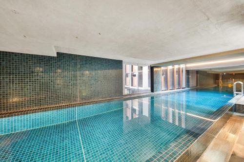 a swimming pool in a building with blue tile at Stylish Central Braddon 1 Bed, Pool, Gym, Parking in Canberra