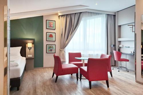a hotel room with a table and chairs and a bed at Garner Hotel Stuhr - Bremen A1 by IHG in Bremen