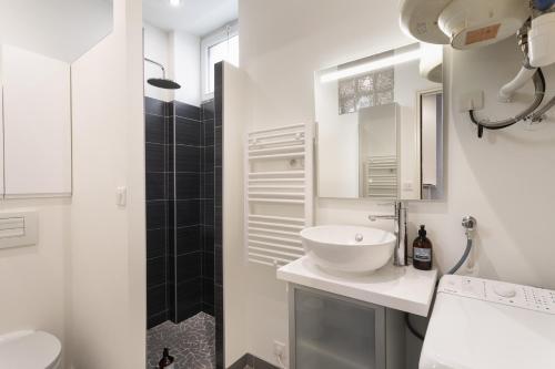 une salle de bain blanche avec lavabo et douche dans l'établissement Le Soleya, à Dinard