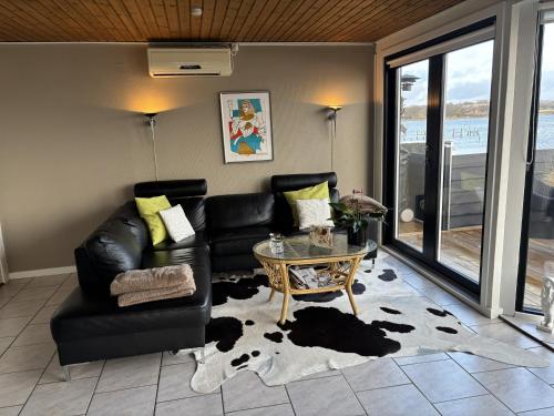 a living room with a black leather couch and a table at Feriebolig smukt beliggende i vandkanten in Munkebo