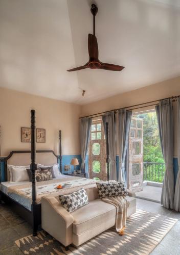 a bedroom with a bed and a couch and a ceiling fan at LohonoStays Calisto Villa E in Camorlim