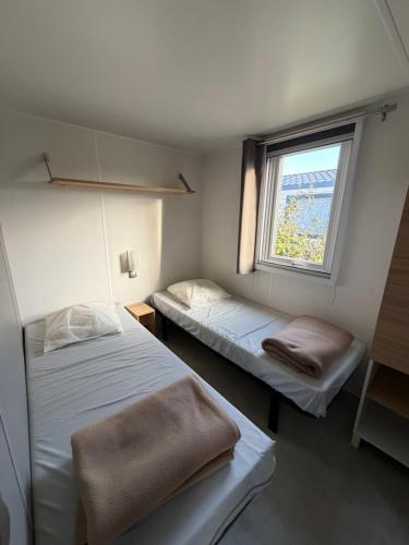 two beds in a small room with a window at Camping L' Arlesienne in Arles