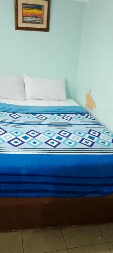 a bed with a blue comforter on top of it at Hotel tower one in Guayaquil