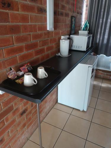 a black table with two mugs on it next to a brick wall at PROSERPINE MOTOR LODGE in Proserpine