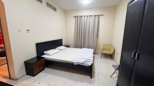 a small bedroom with a bed and a yellow chair at Room for rent daily and monthly in Ajman 