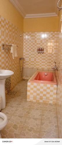 a bathroom with a red tub and a toilet at Hôtel Kolou Wyam in Tcharé