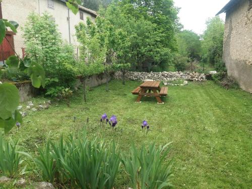 Prades Pyrénées ariegeoise في Entrevennes: طاولة نزهة في حديقة بها زهور أرجوانية