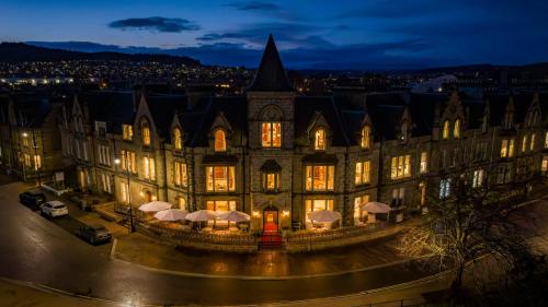 an old building with lights on in a city at night at The Ambassador Hotel in Inverness